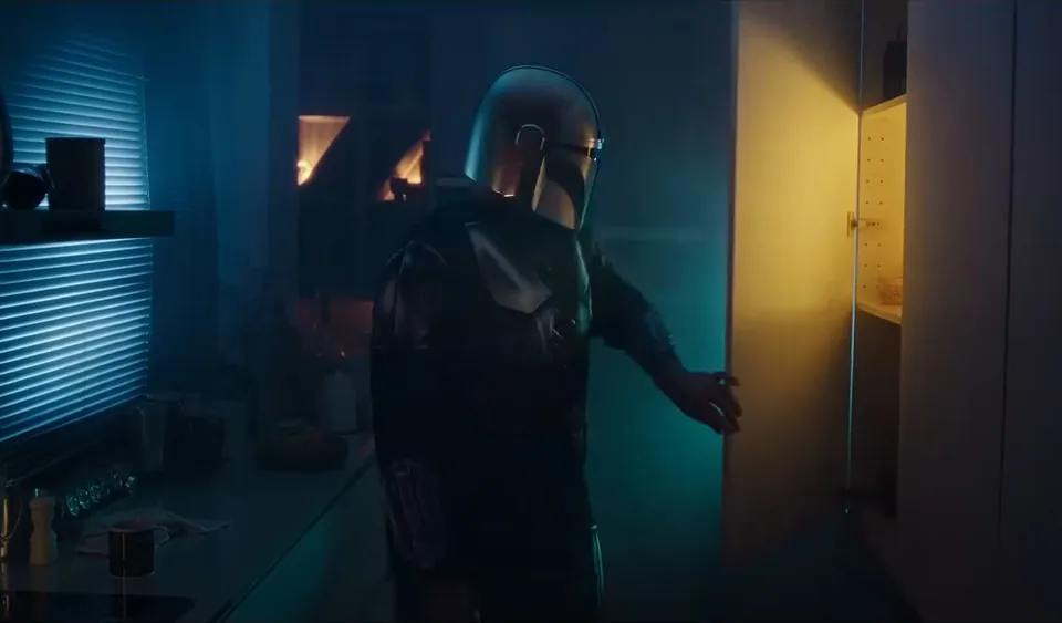El Mandaloriano abre una nevera iluminada en una cocina a oscuras.