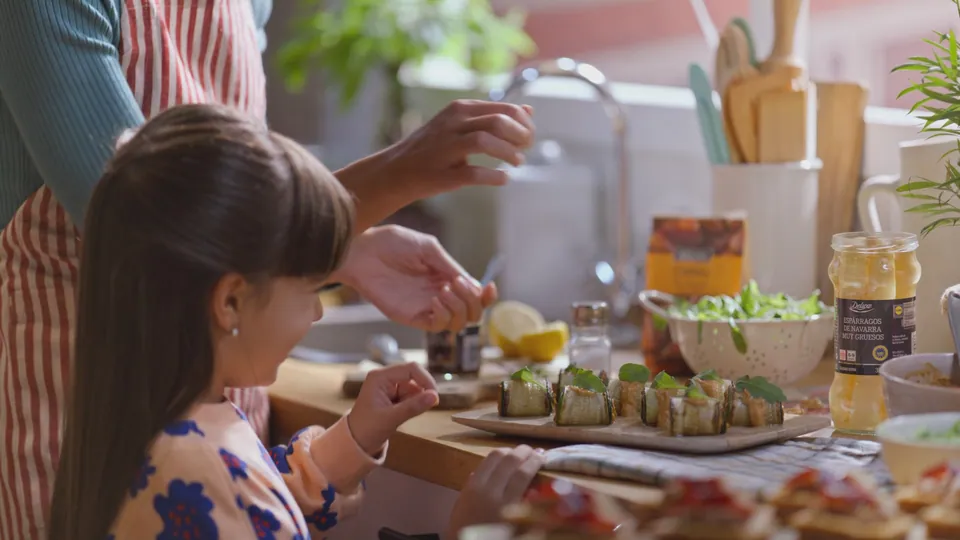 Fotograma: la niña entre platos de comida.