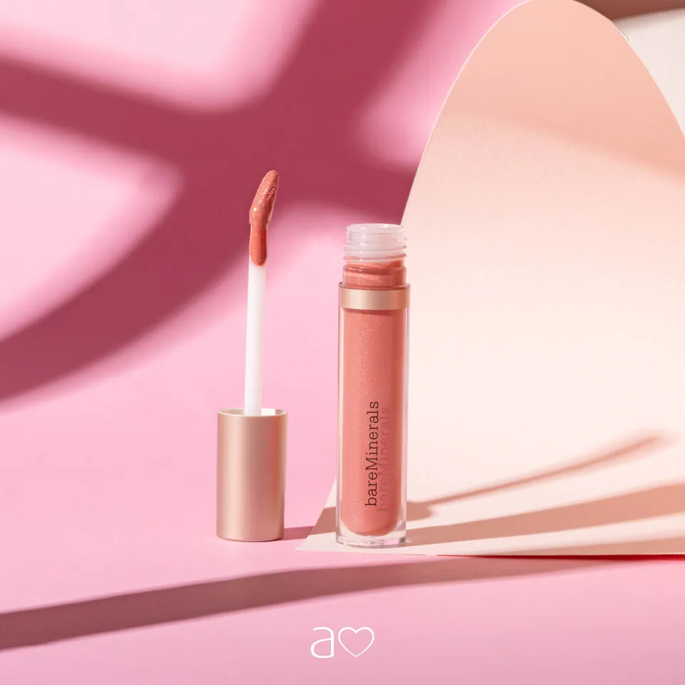 Brillo de labios rosa sobre fondo rosa con sombras.
